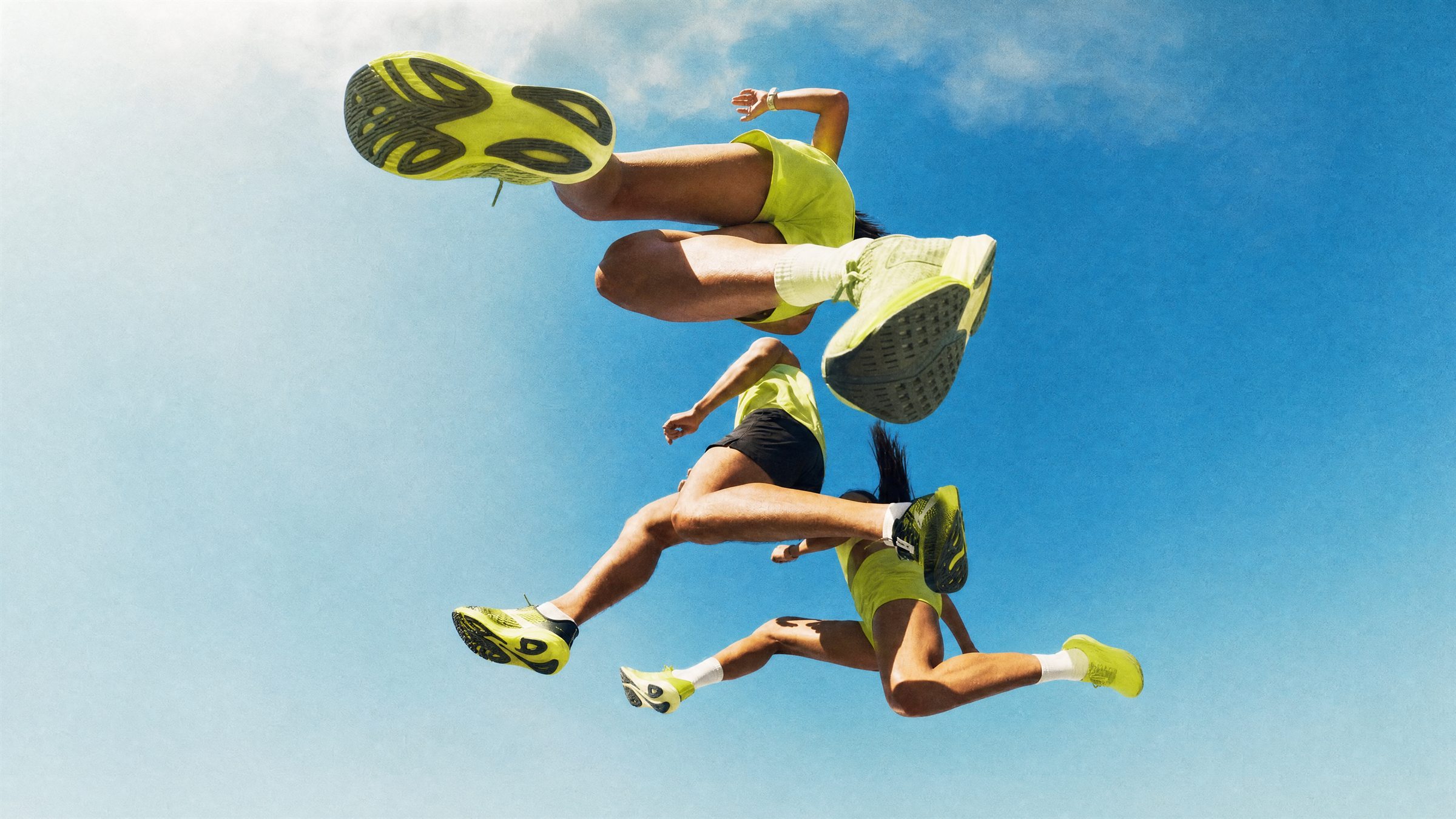 Runners leaping against a blue sky